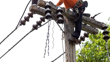 Elektrik direkleri elektrikçiler tarafından bağlanmak için kablo yerleştirilerek onarılıyor. Elektrik direklerinin üst kısmı yalıtıcıya bağlı. Yüksek faizli bir iş. Beyaz özgeçmişi var.