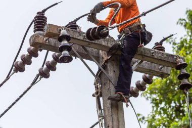 Elektrik direkleri elektrikçiler tarafından bağlanmak için kablo yerleştirilerek onarılıyor. Elektrik direklerinin üst kısmı yalıtıcıya bağlı. Yüksek faizli bir iş. Beyaz özgeçmişi var.