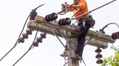 Elektrik direkleri elektrikçiler tarafından bağlanmak için kablo yerleştirilerek onarılıyor. Elektrik direklerinin üst kısmı yalıtıcıya bağlı. Yüksek faizli bir iş. Beyaz özgeçmişi var.