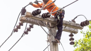 Elektrik direkleri elektrikçiler tarafından bağlanmak için kablo yerleştirilerek onarılıyor. Elektrik direklerinin üst kısmı yalıtıcıya bağlı. Yüksek faizli bir iş. Beyaz özgeçmişi var.