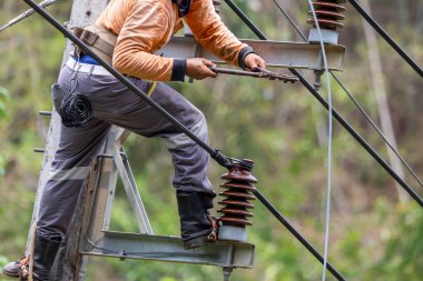 Elektrik direkleri elektrikçiler tarafından bağlanmak için kablo yerleştirilerek onarılıyor. Elektrik direklerinin üst kısmı yalıtıcıya bağlı. Yüksek faizli bir iş..