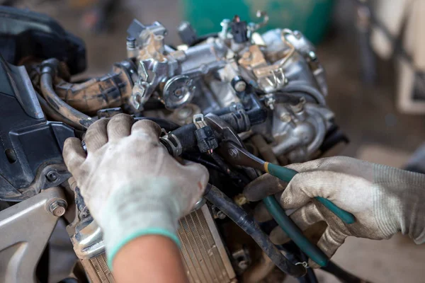 Yakın çekim pense, motorsiklet tamircisi aletleri. Motosiklet gövdesine bağlı lastik hortumları çıkarmak, dükkandaki motosikleti sökmek, otomatik motosikleti sökmek. Tayland 'da bir dükkanda motosiklet tamiri