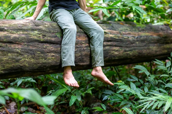 在潮湿的森林里 一个亚洲人赤脚坐在一棵倒下的大树上 木柴上长着苔藓 与自然密切接触的概念 — 图库照片