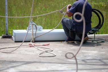 Yeni anten vericileri halatlarla bağlanıyor. Mühendisler 5G sinyaline yükseltmek için mobil ağ anteninin tepesini yüklemek üzere yukarı çekecekler