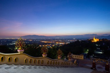 Tapınağın tepesinden manzaraya bakan merdivenlerin görüntüsü. Wat Phra 'nın altın ışığı Doi Saket dağın tepesinde ve Chiang Mai, Tayland' ın ışıkları gece, Haziran 2021.