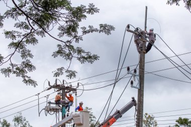 Elektrik direğindeki Taylandlı elektrikçiler kabloları tamir etmek için acele ediyorlar. Yağmur sezonundan önce Chiang Mai, Tayland, 6-11-2021 'deki elektrik kesintisini çözün.