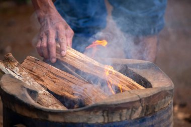 Seçilmiş odun. Yaşlı bir adamın eli sobayı yakacak odunla dolduruyor. Fikirler her zaman yaşlılara ilham verir..