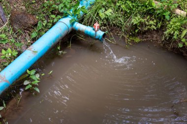 Tarım bahçesindeki mavi PVC boru balık havuzuna su boşaltmak için. metin için arkaplan resmi ve boşluk tarımsal çalılıklarda akan su boruları, dolgu ve boşaltma suyu.