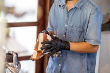 Kafe çalışanlarının ellerine seçici bir şekilde odaklanan siyah lastik eldiven takan barista ellerini her zaman kurulamak için bir havlu kullanıyor. Yemek malzemesi ve temiz yiyecek ve içecek yapmak için.
