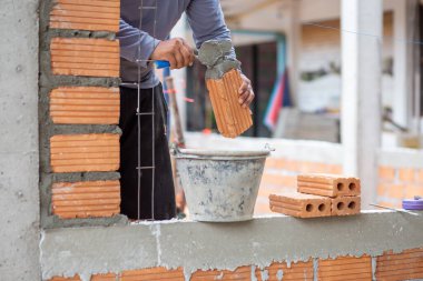Yakından yetenekli bir usta turuncu tuğlaları kullanarak güzel duvarlar ve tasarımlar oluşturacak..