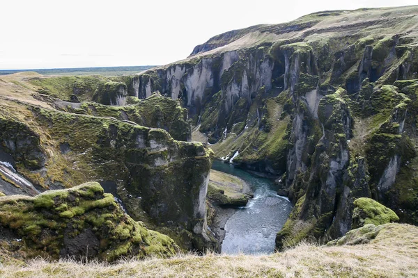 Amazing view of Icelandic deep canyon with green moss, volcano rocks and mountain river