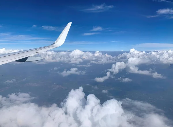 Airplane Window view on white wing and white clouds and infinite horizon by clear sunny weather