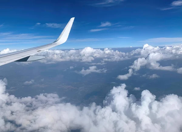 Airplane Window view on white wing and white clouds and infinite horizon by clear sunny weather