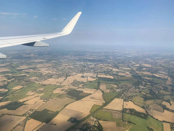 Airplane Window view on white wing and Earth fields and infinite horizon by clear sunny weather from high altitude