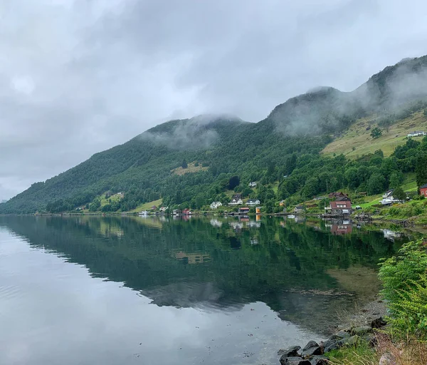 Norway fjords by summer with red and white traditional summer houses at the water\'s edge in a village