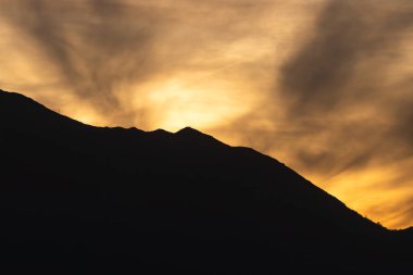 Sarı bir gün batımı ve dağ silueti.