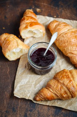 Koyu ahşap arka planda reçelli taze pişmiş kruvasan..