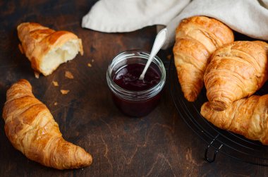 Koyu ahşap arka planda reçelli taze pişmiş kruvasan..