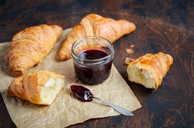 Koyu ahşap arka planda reçelli taze pişmiş kruvasan..