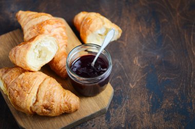 Koyu ahşap arka planda reçelli taze pişmiş kruvasan..