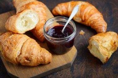 Koyu ahşap arka planda reçelli taze pişmiş kruvasan..
