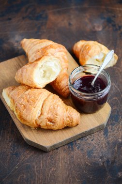 Koyu ahşap arka planda reçelli taze pişmiş kruvasan..