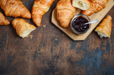 Koyu ahşap arka planda reçelli taze pişmiş kruvasan..