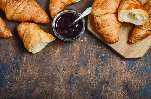 Koyu ahşap arka planda reçelli taze pişmiş kruvasan..