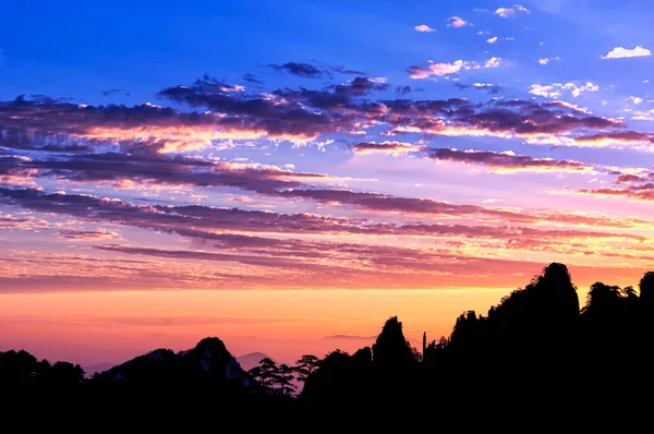 Çin 'in Anhui Eyaleti' ndeki Sarı Dağ 'daki (Huangshan) dağların siluetinin üzerinde çarpıcı bir gündoğumu..