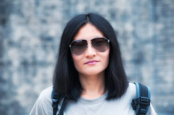 一个美丽的微笑的中国女人戴着太阳镜站在西安城墙上 灰墙建筑的背景模糊不清 — 图库照片