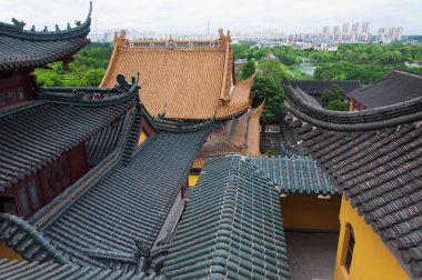 Jiangsu şehrinin bulutlu bir gününde arka planda Zhenjiang şehri ile birlikte Jinshan Tapınağı 'nın çatısına bakıyoruz..
