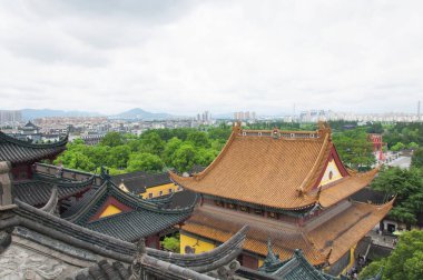 Jiangsu şehrinin bulutlu bir gününde arka planda Zhenjiang şehri ile birlikte Jinshan Tapınağı 'nın çatısına bakıyoruz..