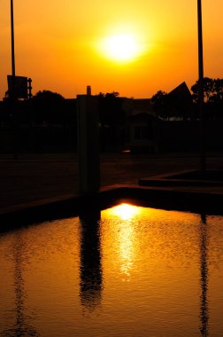 Gün batımında Şangay 'da sulara yansıyan turuncu ve sarı batan güneş ve binaların ve nesnelerin siluetleri..