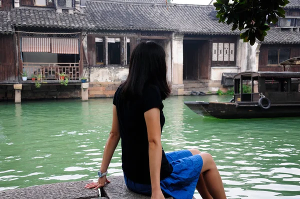 中国の女性は 中国浙江省の東莞市西風光明媚な地域の水運河の端にボートで移動するとして座っている — ストック写真
