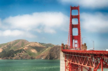San Francisco California 'daki mavi gökyüzüne karşı arka planda Marin Hills ile birlikte Golden Gate köprüsünden geçen arabalar..
