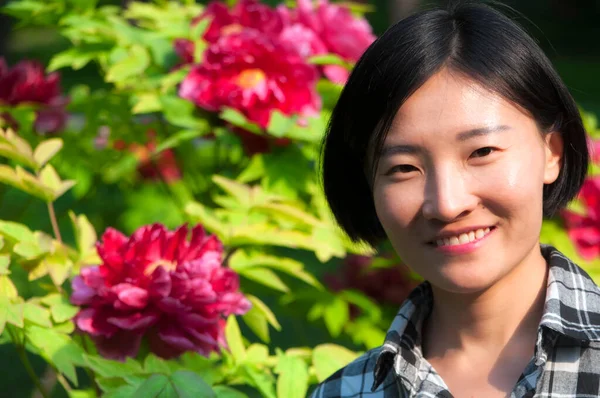 中国景山公园 一位笑容满面的中国妇女 她的背景是开花的牡丹 — 图库照片