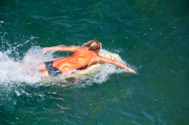 Tanınmayan bir sörfçü batı kıyısındaki Manhattan sahilindeki dalgaları yakalamak için kürek çekiyor..