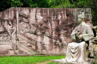 Wuyishan 'daki Sanqingdian' da çay içen Çinli bir adamın eskimiş taş duvar resmi ve heykeli veya Çin 'in Fujian bölgesindeki Wuyi Dağı manzarası..  