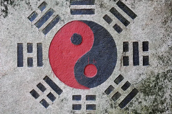 A black and red yin and yang symbol in important in Taosim on a wall.