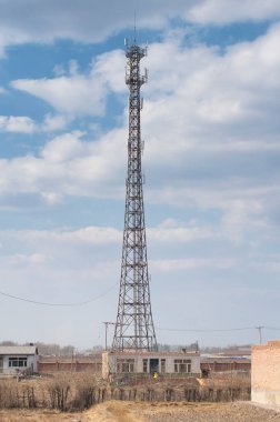 Kuzeydoğu Çin 'in Zhaodong şehrinde güneşli bir günde kırsal bir bölgenin üzerinde yükselen büyük metal bir baz istasyonu..  