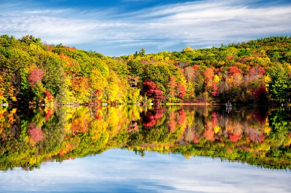 The colorful trees of Autumn reflecting off of the waters in Burr State Park in Torrington, Connecticut on a sunny fall day.