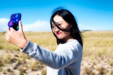 Truro Massachusetts 'in Cod Ulusal Deniz Burnu' nda güneşli bir günde Çinli bir kadın selfie çekiyor..