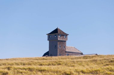 The tower and exterior of the old harbor life saving station rising above the grass covered dunes on the national seashore at race point in provincetown, cape cod massachusetts. 