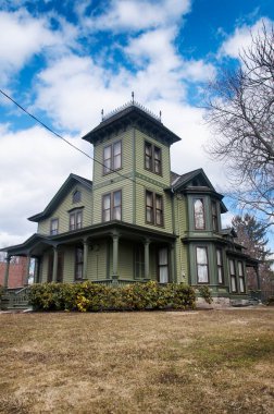 A green victorian style historic building located on main street in torrington connecticut on a late winter day. 