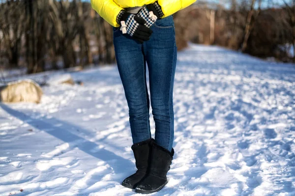 A woman\'s lower half of body wearing jeans, gloves, and yellow winter jacket on a snowy path in sheffield Massachusetts.