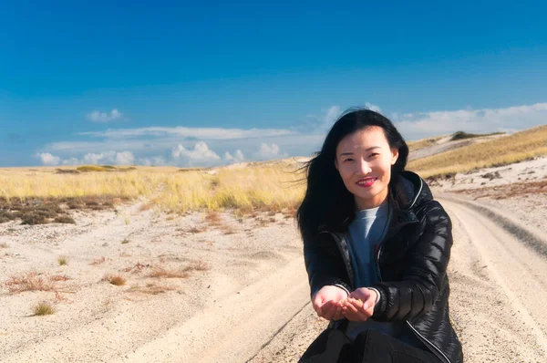 在一个阳光灿烂的蓝天 一位中国妇女坐在国家海滨风景区的轮胎轨道之间的沙滩上 — 图库照片