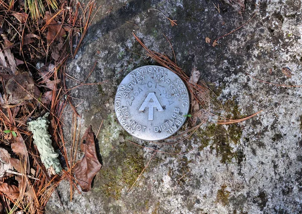 An Appalachian Trail survey marker imbedded into rock within Falls Village Connecticut.