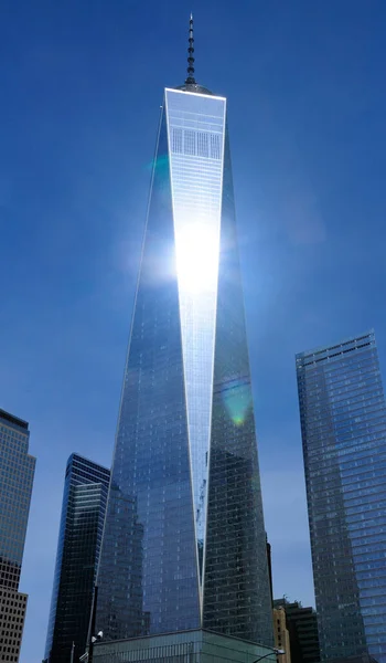 The freedom tower rising up above the Manhattan Skyline in New York City as the sun reflects off of the glass windows.