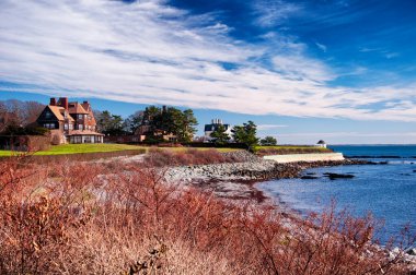 Newport Rhode Island 'ın kayalık kıyıları ve uçurumları mavi gökyüzü ve beyaz bulutların altında..