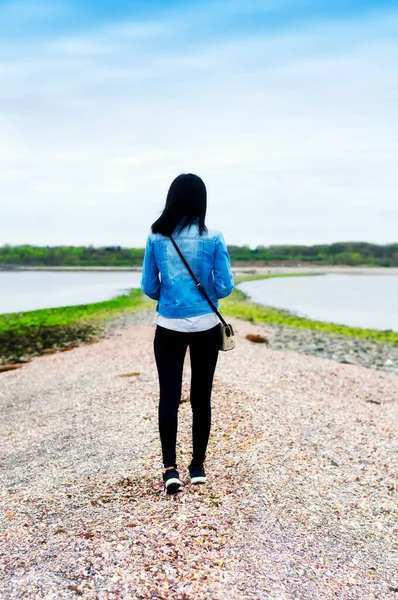 A chinese woman walking on a sandbar at lowtide from charles island to silver sands state park in Milford connecticut.